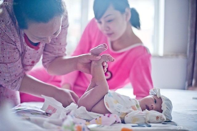 沈阳人月嫂边阳正在给刚出生20天的"团团"换尿布,孩子母亲在一旁看着