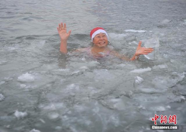 2015年12月24日,哈尔滨,民众戴着圣诞帽在入零下26℃的松花江中冬泳
