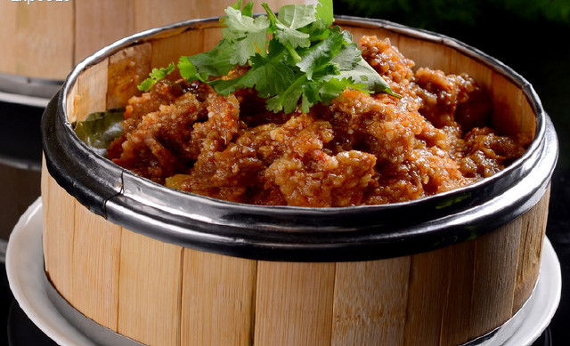 4,上菜时将笼下垫一盘,并在牛肉上加辣椒粉,花椒粉,葱花,蒜泥,香菜